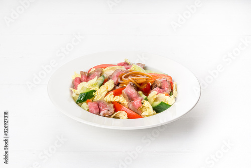 Salad in a white plate with roast beef, fresh cucumber, pepper.
