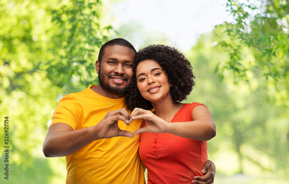 love, valentines day and people concept - happy african american couple making hand heart gesture over green natural background love, valentines day and people concept - happy african american couple making hand heart gesture over green natural background