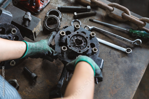 Industrial plant worker repairing car parts in auto repair workshop - Mechanical engineer inspecting and adjusting vehicle part - Manufacturing factory, student apprentice and skilled work concept