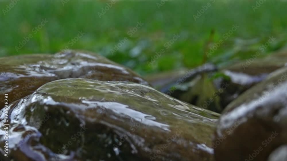 Raindrops splashing against rocks in slow motion with green natural background; depth of field Raindrops splashing against rocks in slow motion with green natural background; depth of field