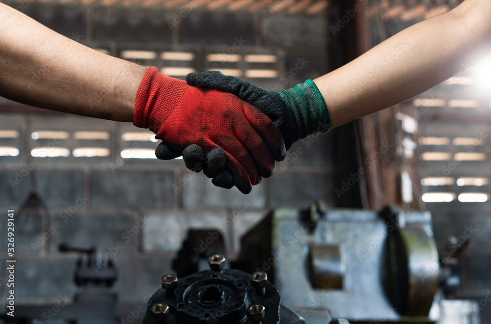 Male and female industrial workers shaking hands in factory workshop wearing protective workwear - Business and commercial teamwork within the workplace - Working together, goals and success concept Male and female industrial workers shaking hands in factory workshop wearing protective workwear - Business and commercial teamwork within the workplace - Working together, goals and success concept