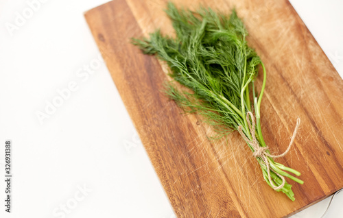 greens, culinary and ethnoscience concept - bunch of dill on wooden cutting board