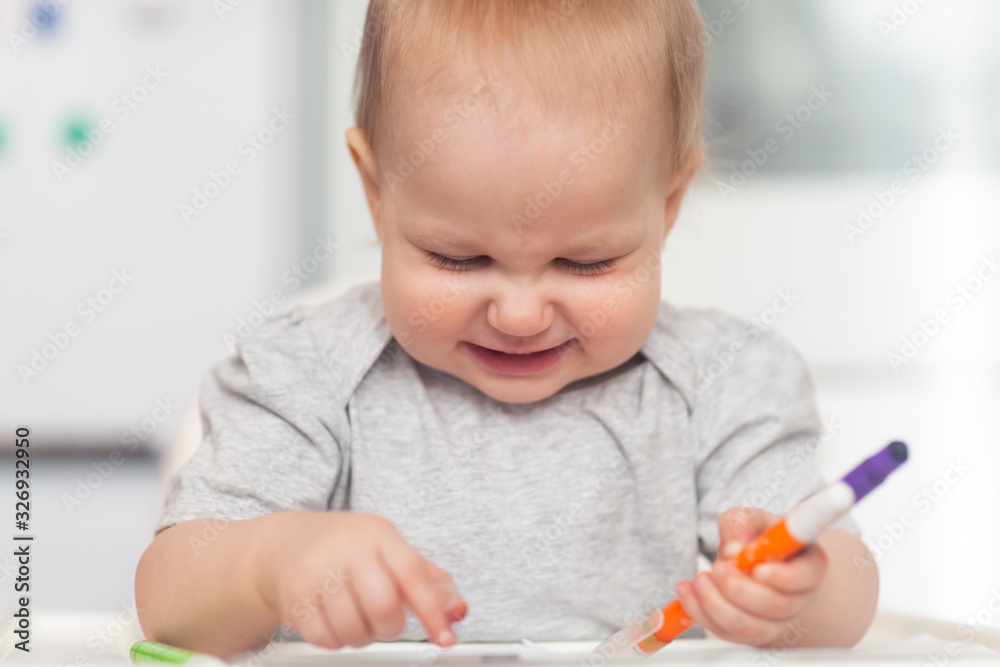 Cute baby paint using colorful pencils on white table Cute baby paint using colorful pencils on white table