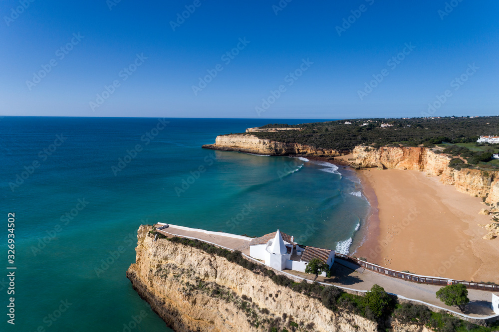 Aerial drone photo of the beaitiful Praia da Senhora da Rocha (Senhora da Rocha Beach) with the white chapel on the roks, near Armacao de Pera, Algarve, Portugal