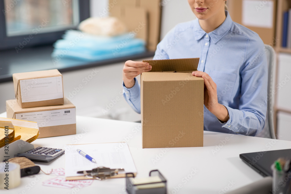 delivery, mail service, people and shipment concept - close up of woman packing parcel box at post office delivery, mail service, people and shipment concept - close up of woman packing parcel box at post office