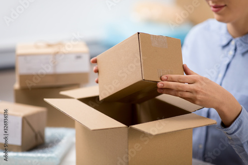 delivery, mail service, people and shipment concept - close up of woman packing parcel box at post office © Syda Productions