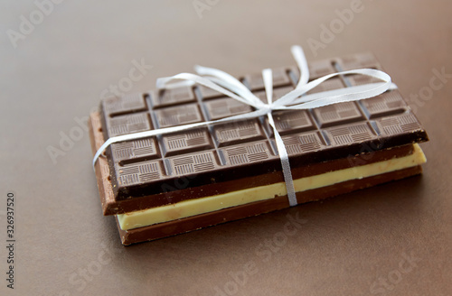 sweets, confectionery and food concept - different kinds of chocolate tied with white ribbon on brown background