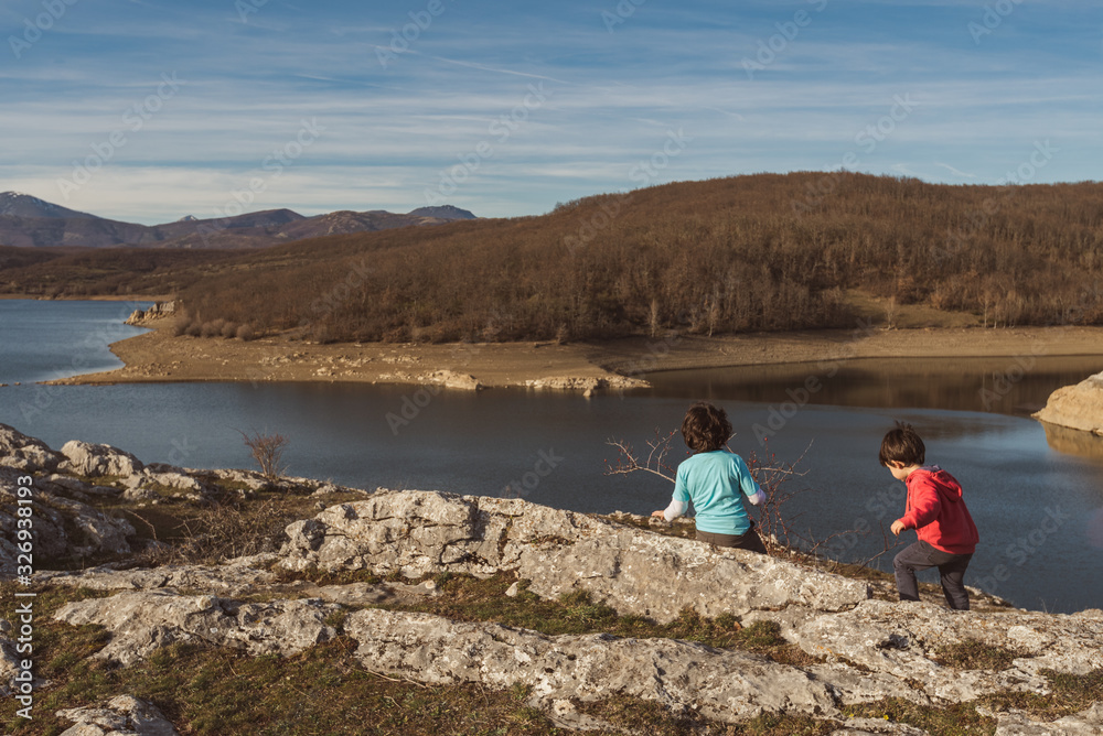 two little kids hiking in the mountains of Palencia, Spain, during the winter ending and the spring beginning in a warm sunny day