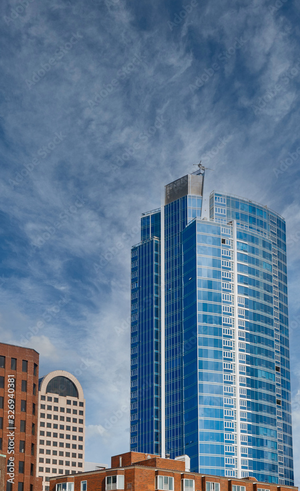 A modern blue glass office tower rising from classic older buildings in Seattle