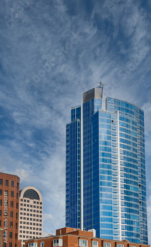 A modern blue glass office tower rising from classic older buildings in Seattle