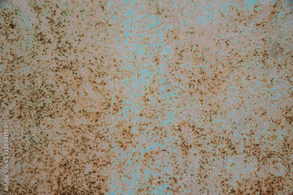 Small patches of light blue pastel paint on an old metal surface with rust spots and scratches. Abstract background, texture. Small patches of light blue pastel paint on an old metal surface with rust spots and scratches. Abstract background, texture.