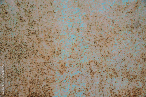 Small patches of light blue pastel paint on an old metal surface with rust spots and scratches. Abstract background, texture.