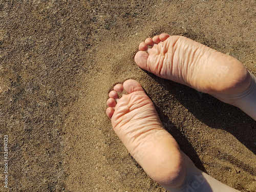 The feet of a woman facedown lying on the sand beach