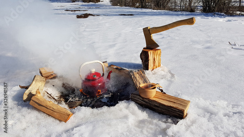 red teapot in campfire and wooden kuksa