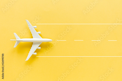 Model white plane, airplane on yellow background. Top view, flat lay. Travel, vacation concept.