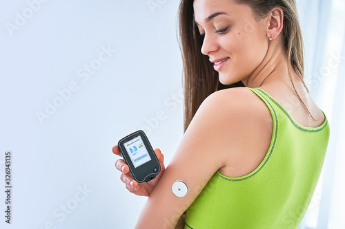 Woman diabetics control and checking glucose level with a remote sensor. Continuous monitoring glucose levels without blood. Medical technology in sugar diabetes treatment