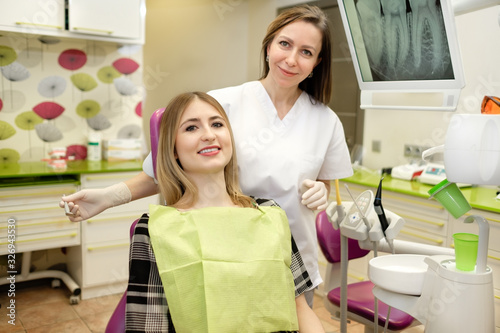 People, medicine, stomatology and health care concept - happy female dentist with patient girl at dental clinic office