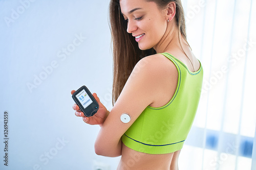 Woman diabetics checking glucose level with a remote sensor. Continuous monitoring and control glucose levels without blood. Technology in diabetes treatment and health care