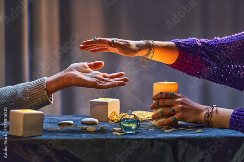 Foto Gypsy witch woman during palmistry and divination ritual around candles and other magical accessories