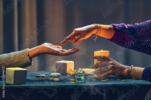 Magic gypsy woman reading palm lines around candles and other magical accessories. Witch during fortune telling palmistry, prediction the future life and divination ritual