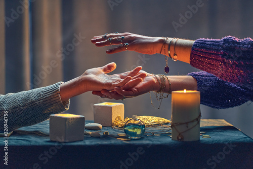 Foto Witch woman spelling over hand palm during occult spiritual rite and divination ritual around candles and other magical accessories