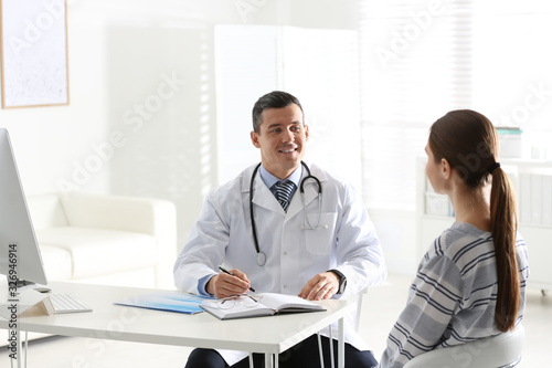 Doctor consulting patient at desk in clinic