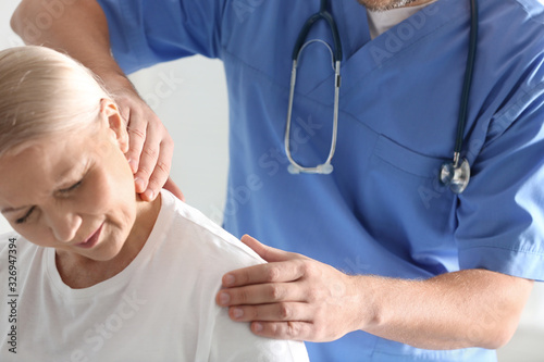 Male orthopedist examining patient with injured neck, closeup photo