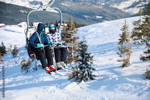 People using chairlift at mountain ski resort, space for text. Winter vacation photo