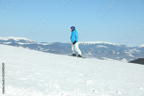 Male snowboarder on snowy slope in mountains. Winter vacation