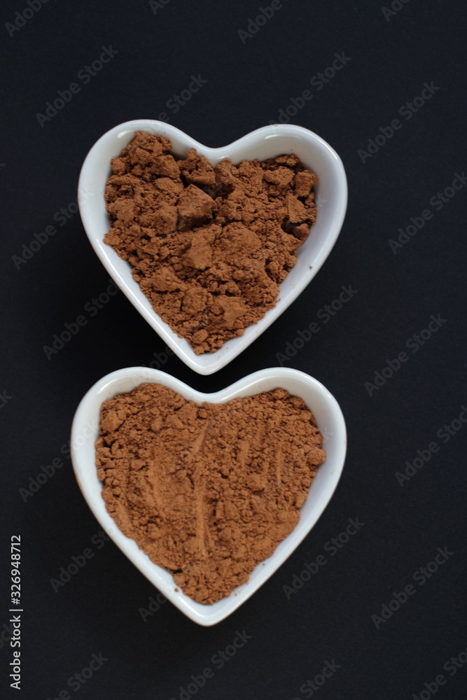 Guarana powder in plates hearts on a black background. Guarana powder in plates hearts on a black background.