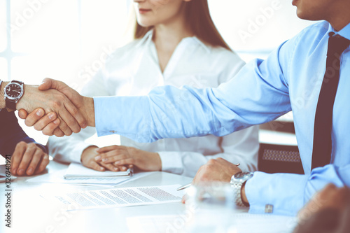 Business people shaking hands at meeting or negotiation  close-up. Group of unknown businessmen and women in modern office. Teamwork  partnership and handshake concept  toned picture