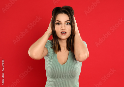 Beautiful young woman posing on red background © New Africa