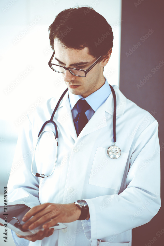 Doctor man using tablet computer for network research or virtual disease treatment. Perfect medical service in clinic. Modern medicine, medic data and healthcare concepts Doctor man using tablet computer for network research or virtual disease treatment. Perfect medical service in clinic. Modern medicine, medic data and healthcare concepts