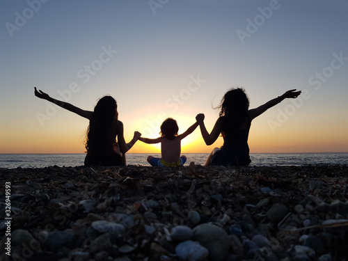 a little boy watching the sunset at the beach with two young girls.