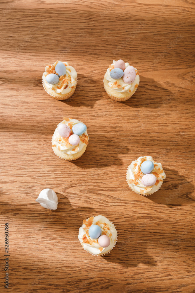 Top view of delicious cupcakes with decorative bunny on wooden background Top view of delicious cupcakes with decorative bunny on wooden background