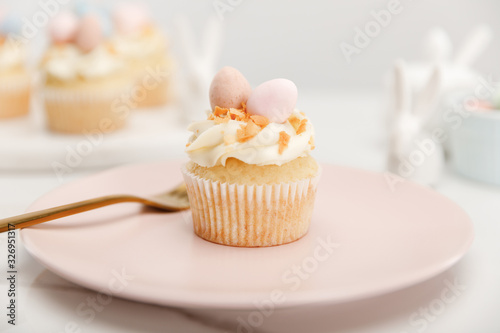 Selective focus of cupcake on plate with fork on grey background