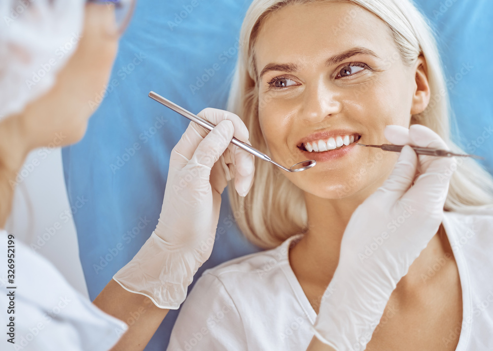 Smiling blonde woman examined by dentist at dental clinic. Healthy teeth and medicine concept Smiling blonde woman examined by dentist at dental clinic. Healthy teeth and medicine concept
