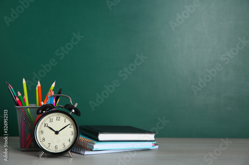 Alarm clock and school stationery on white wooden table, space for text. Doing homework photo