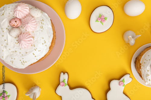 Fototapeta Naklejka Na Ścianę i Meble -  Top view of easter cakes with chicken eggs, cookies and decorative bunnies on yellow background