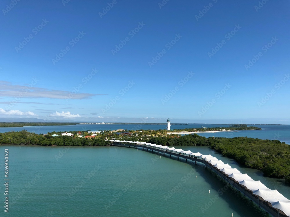 Wide shot of Harvest Caye island, with the covered walkway and the lighthouse in the distance.