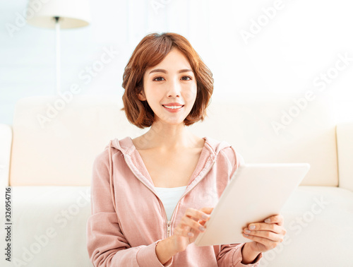 Happy casual beautiful woman working on tablet  at home