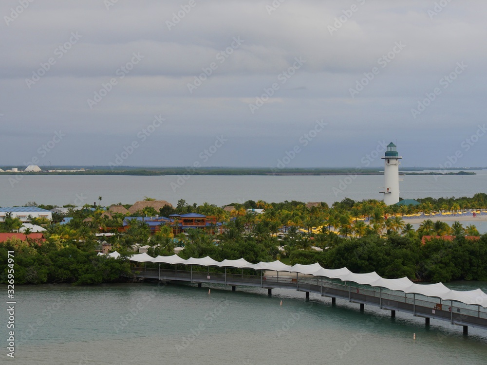 Medium wide shot of Harvest Caye in Belize, with the covered walkway and lighthouse in the distance.