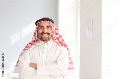 Cuadro en lienzo Positive arabic man smiling while standing in a white bright room
