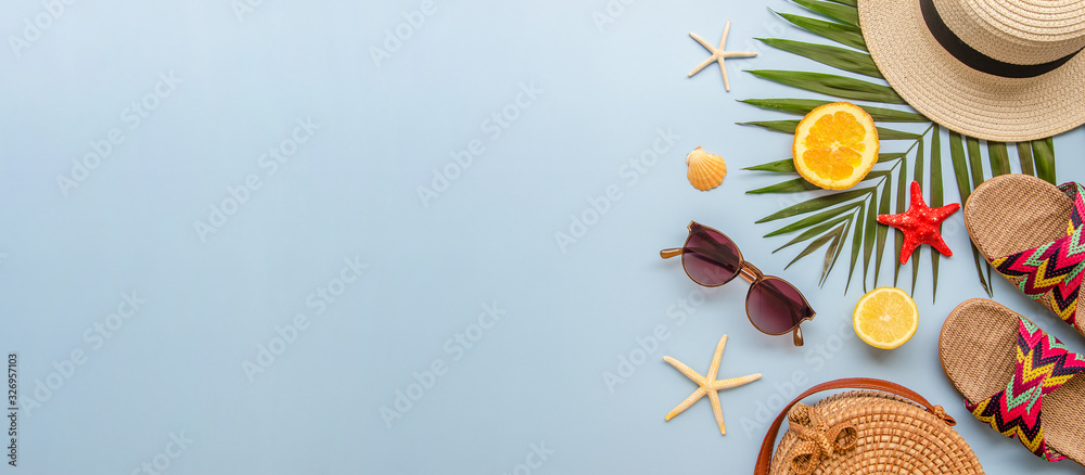 Top view summer banner with palm leaves and female beach accessories on a blue background. Rattan bag, sunglasses, hat and flip flops with copy space - obrazy, fototapety, plakaty 