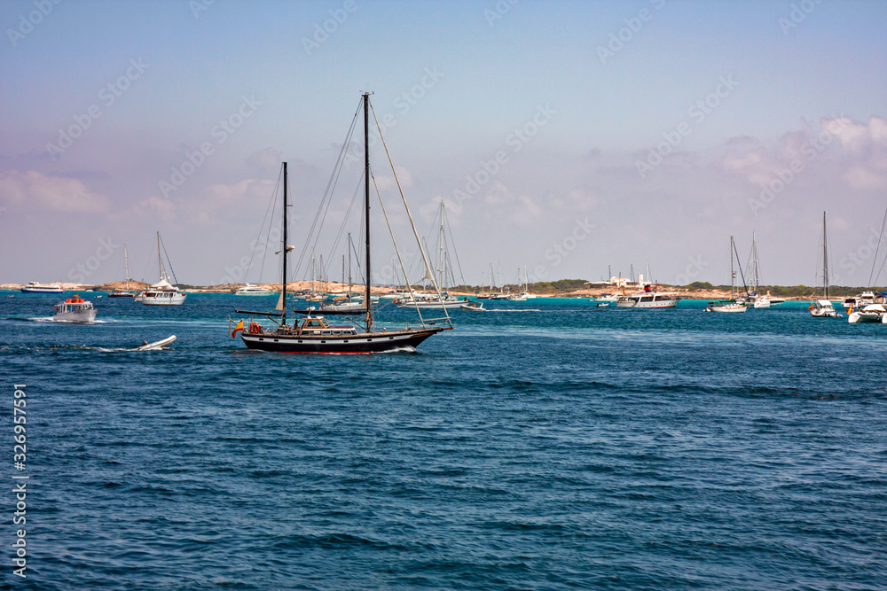 Some sailboats and yachts in the sea between Ibiza and Formentera in the Balearic islands in Spain.