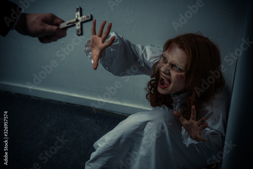 exorcist holding cross in front of screaming obsessed girl