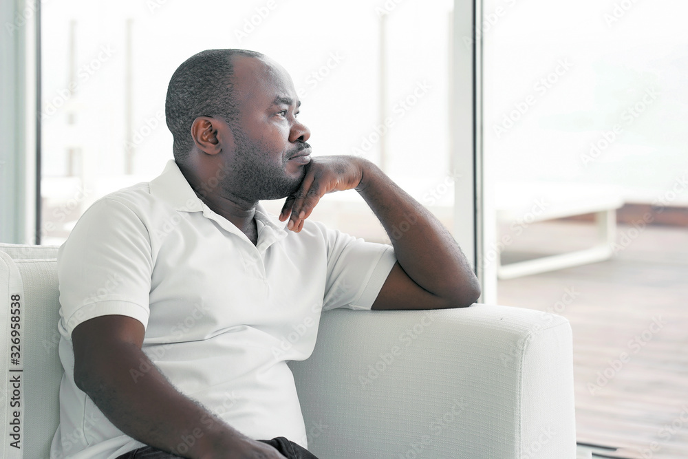 Fototapeta premium Sad face depressed elderly african man. Very sad elderly man. Portrait of a sad elderly man close-up. Lonely african elderly man is sad sitting on the bed at home. 
