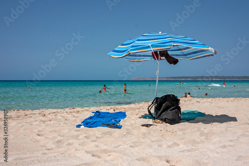 Towels and umbrella on a sandy beach in Formentera in the Balearic Islands in Spain.
