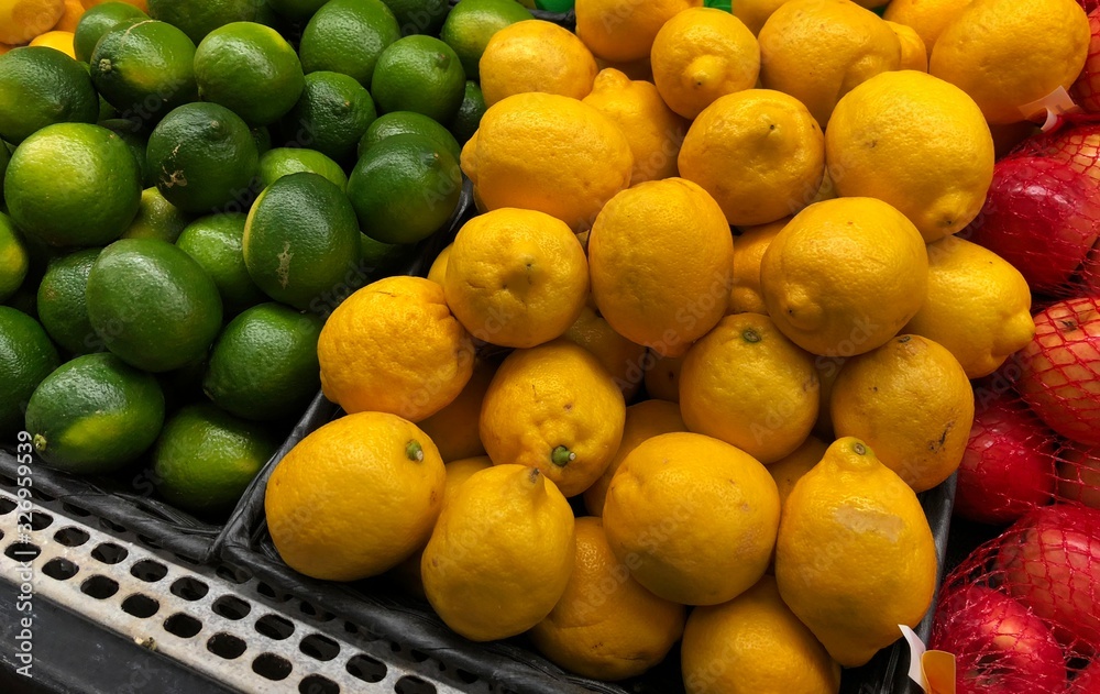 Piles of fresh lime and lemon fruits at the fresh produce section of a market