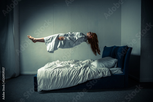 obsessed girl in nightgown sleeping and levitating over bed Stock Photo